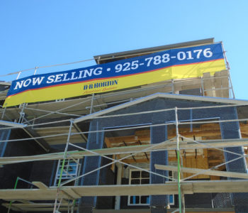 Large format inkjet banner installed on multi-story building's scaffolding platform.