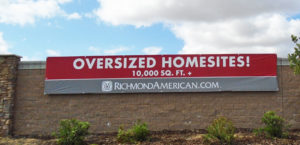 Red and grey, large format banner installed on a large sound wall displaying Over-sized Home-sites