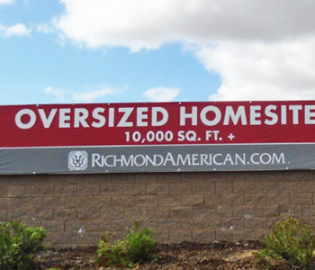 Red and grey, large format banner installed on a large sound wall displaying Over-sized Home-sites