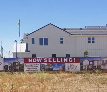 Large format banner displayed across fence on an empty lot.