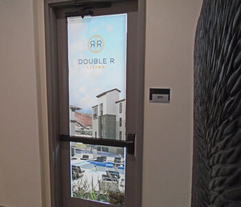 Single door with branding printed on vinyl applied to window of door.