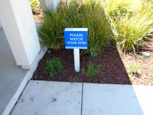 A branded sign stating "Please watch your step"