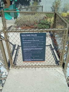 Dog Park Rules sign installed on metal gate.