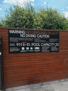 Large pool sign installed on wood wall.